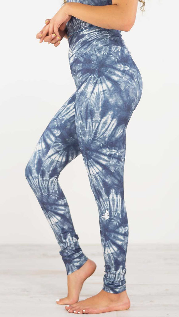 Left side view of model wearing the indigo spiral athleisure leggings. They are in a indigo color and have white tie dye spirals throughout the leggings