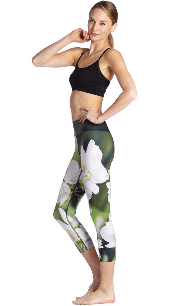 left side view of model wearing white jasmine flower themed printed capri leggings