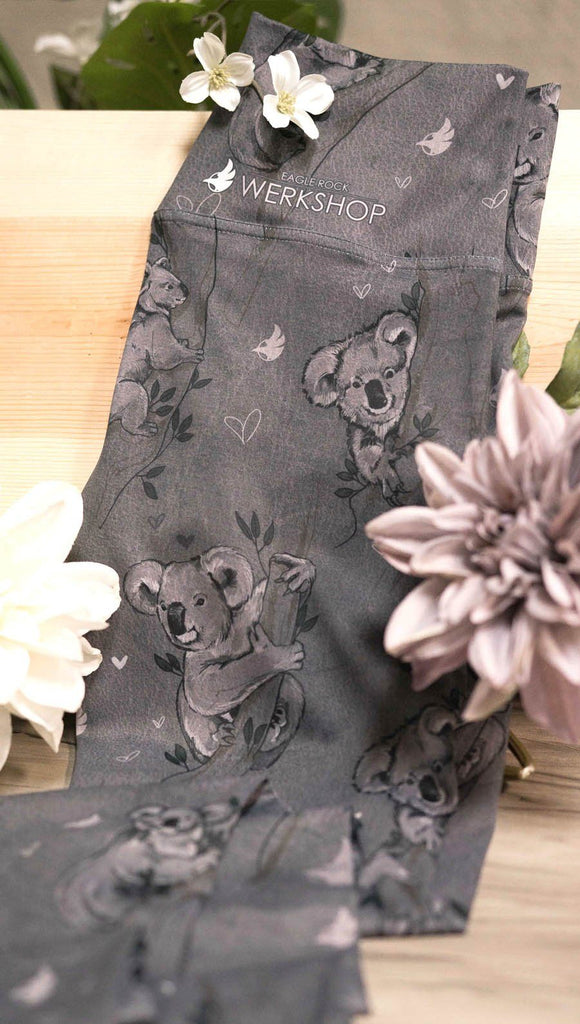 Koala leggings with tree branches and leaves sitting on a table with flowers