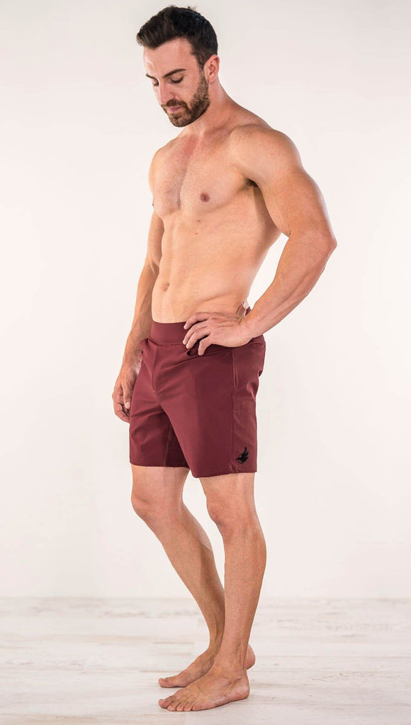 Diagonally left side view of model wearing men's oxblood performance shorts with slim fit
