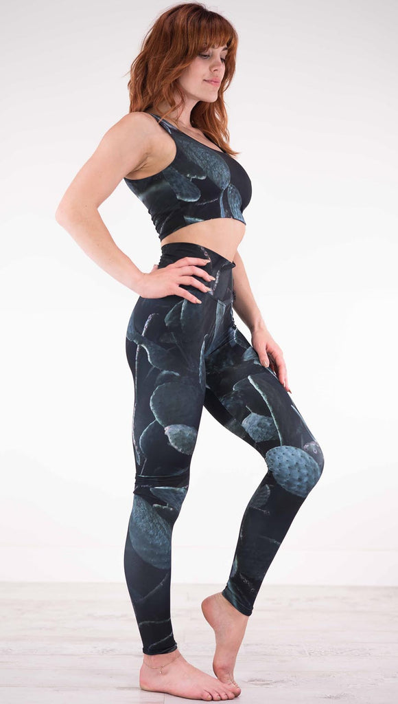 Right view of model wearing black athleisure leggings with dark green cacti plants throughout