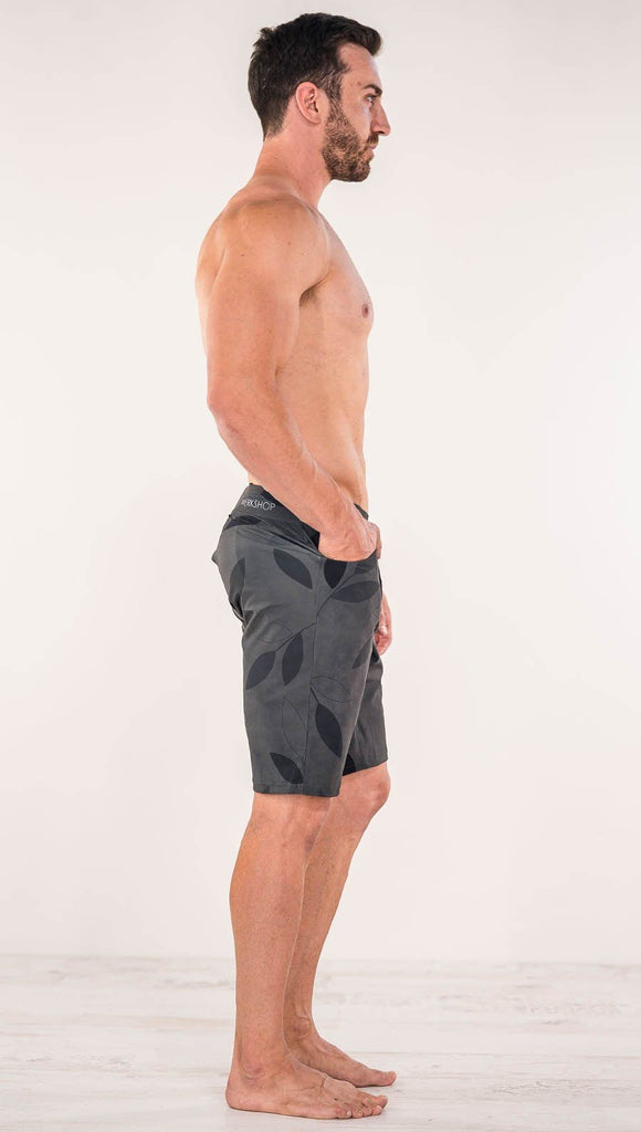 Right side view of model wearing gray printed performance shorts with slim fit and vilva leaf inspired art