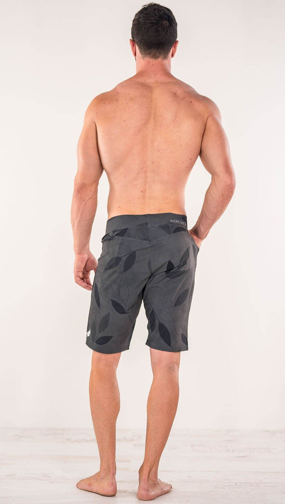 Back side view of model wearing gray printed performance shorts with slim fit and vilva leaf inspired art