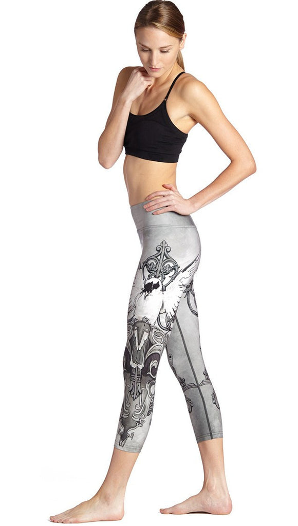 left side view of model wearing black and white fantasy dove themed printed capri leggings