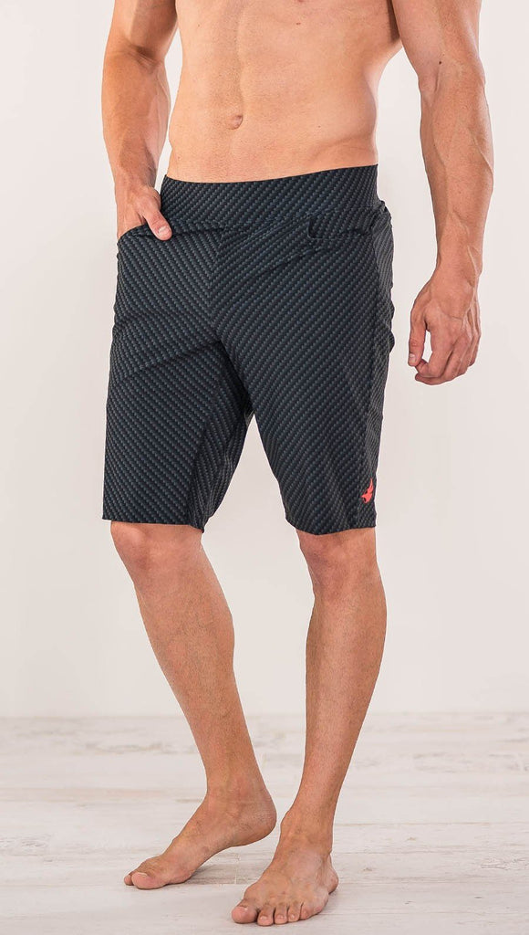 Close up front view of model wearing men's black printed performance shorts with slim fit and carbon fiber inspired art.