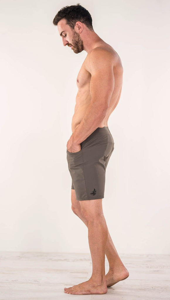Left side view of model wearing men's taupe performance shorts with slim fit
