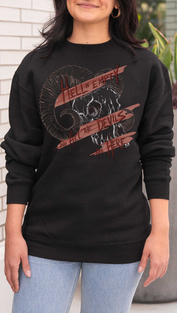 Person wearing a black sweatshirt with a graphic design and text. Featuring a gothic skull and the quote, "Hell is Empty and the Devils Are All Here" from the Temptest by William Shakespeare
