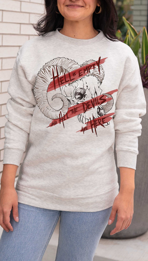 Person wearing a gray sweatshirt with a graphic design and text. Featuring a gothic skull and the quote, "Hell is Empty and the Devils Are All Here" from the Temptest by William Shakespeare