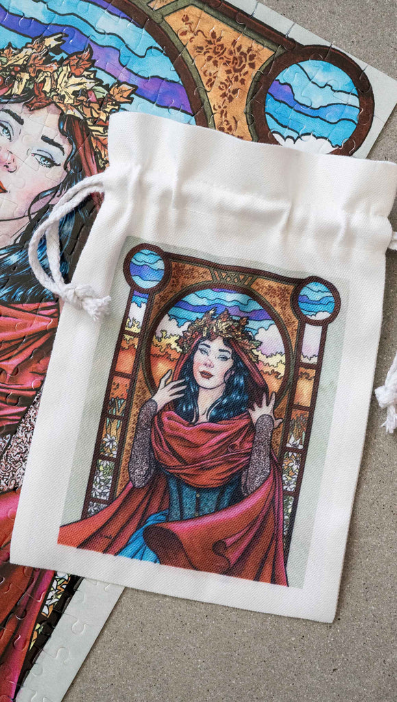 Matching drawcord pouch for Art Nouveau Puzzle featuring original artwork by Scott Christian Sava. The painting features a woman with a cloak and crown of autumn leaves standing in front of a stained glass window.