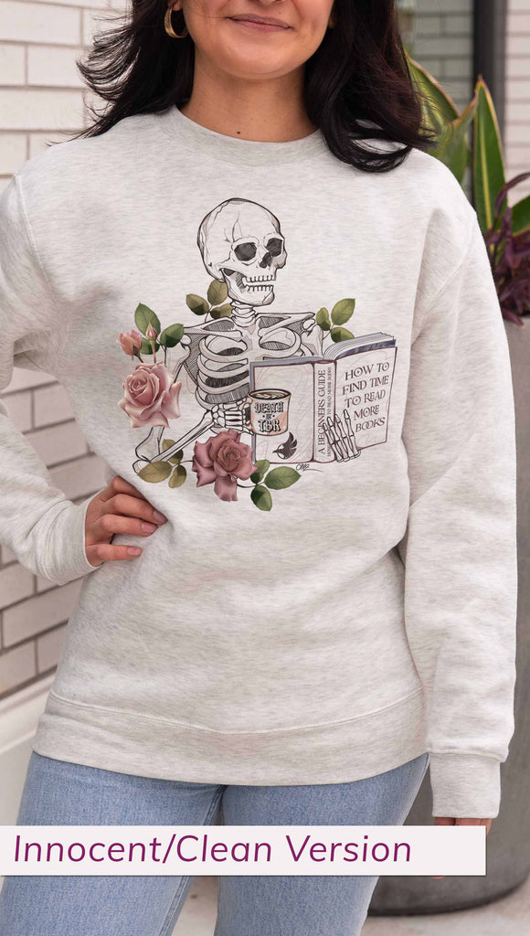 Person wearing a light gray (oatmeal) sweatshirt with a skeleton and floral design, standing outdoors. The pullover features the bookish phrases, "Death by TBR" and "A Beginners Guide: How to Find Time to Read More Books"
