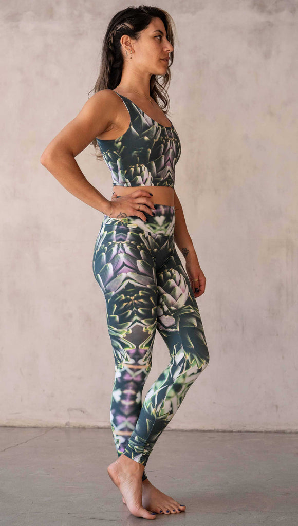 Girl wearing WERKSHOP Artichoke Athleisure Leggings. The leggings show a photo-real fractal inspired edit of artichokes. It has pops of bright green and bright purple over a mostly dark green base. It is a very geometric and fractal design.