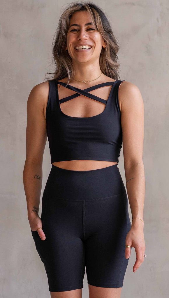 Model wearing WERKSHOP Four Way Reversible Top in EnviSoft Fabric. She is wearing the Black side out in this photo with the “X” detail in the front.