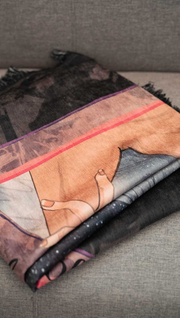 WERKSHOP soft chenille tapestry with a original and exclusive artwork of a fae man passionately kissing a woman. The phrase on the artwork says, "daydreaming of my 500 year old fae book boyfriend" on top and "touch her and die' on the bottom. the background is a distressed dark mauve with charcoal splatter. Folded on a gray sofa.