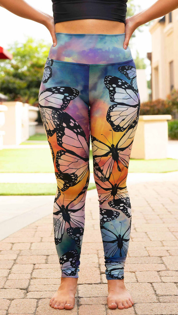 Girl wearing WERKSHOP Butterflies Athleisure Leggings. The artwork on the leggings features a black outline of monarch butterflies over a rainbow coloured watercolor background.