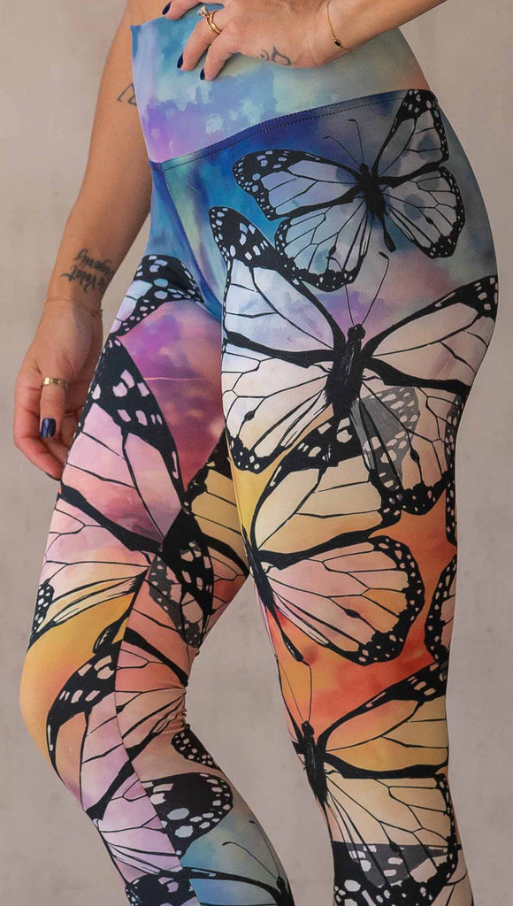 Girl wearing WERKSHOP Butterflies Athleisure Leggings. The artwork on the leggings features a black outline of monarch butterflies over a rainbow coloured watercolor background.