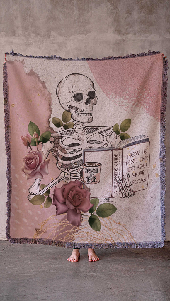 Blanket with a skeleton and floral design on a textured surface. with the phrases, "Death by TBR" and "How to Find Time to Read more Books"