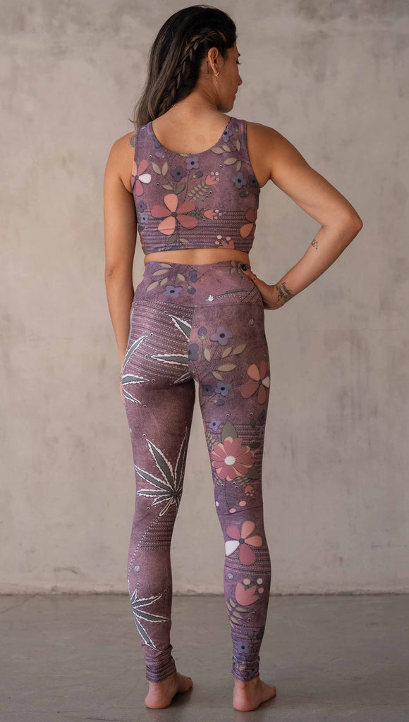 Model wearing WERKSHOP Dope + Flowers Mashup leggings. The leggings are printed with original artwork by Chriztina Marie. One leg features patchwork daisys over grainy mauve toned leather background. The other leg features marijuana leaves over a warm brown background. Both legs have faux stitching.