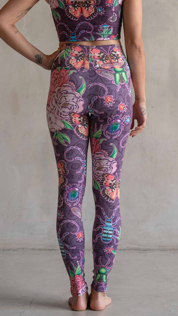 Back view of model wearing WERKSHOP Enchanted Garden Athleisure Leggings. The fabric is printed with original artwork by our Female Founder, Chriztina Marie. The artwork printed not the fabric features Butterflies, Beetles and Peonies over a warm fuchsia with bright bold pops of color on each beetle and Butterfly.