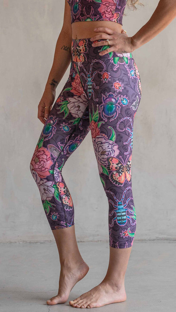 Side view of model wearing WERKSHOP Enchanted Garden Capri Length Triathlon Leggings. The fabric is printed with original artwork by our Female Founder, Chriztina Marie. The artwork printed not the fabric features Butterflies, Beetles and Peonies over a warm fuchsia with bright bold pops of color on each beetle and Butterfly.