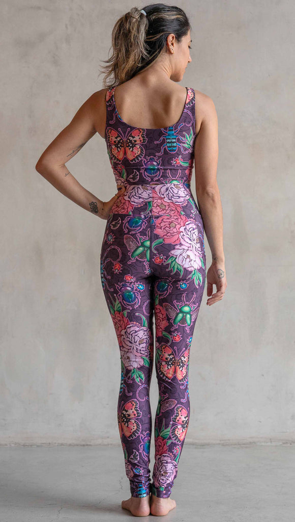 Full body back view of model wearing WERKSHOP Enchanted Garden EnviSoft Leggings with Pockets. The fabric is printed with original artwork by our Female Founder, Chriztina Marie. The artwork printed not the fabric features Butterflies, Beetles and Peonies over a warm fuchsia with bright bold pops of color on each beetle and Butterfly.