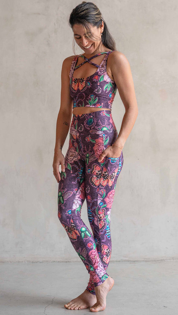 Full body front view of model wearing WERKSHOP Enchanted Garden EnviSoft Leggings with Pockets. The fabric is printed with original artwork by our Female Founder, Chriztina Marie. The artwork printed not the fabric features Butterflies, Beetles and Peonies over a warm fuchsia with bright bold pops of color on each beetle and Butterfly.