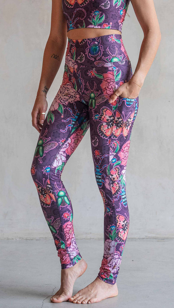 Front view of model wearing WERKSHOP Enchanted Garden EnviSoft Leggings with Pockets. The fabric is printed with original artwork by our Female Founder, Chriztina Marie. The artwork printed not the fabric features Butterflies, Beetles and Peonies over a warm fuchsia with bright bold pops of color on each beetle and Butterfly.