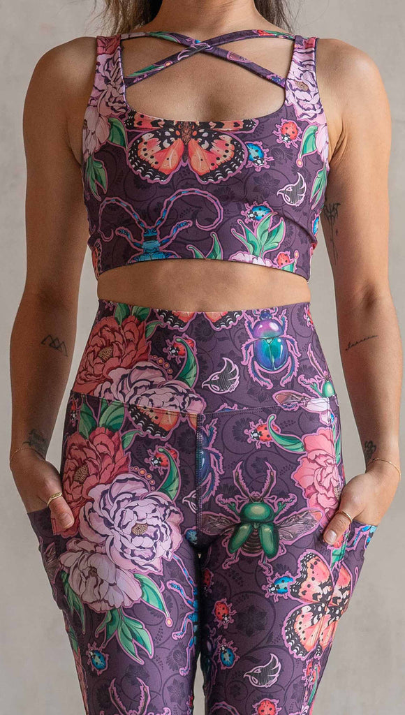 Zoomed in view of model wearing WERKSHOP Enchanted Garden EnviSoft Leggings with Pockets. The fabric is printed with original artwork by our Female Founder, Chriztina Marie. The artwork printed not the fabric features Butterflies, Beetles and Peonies over a warm fuchsia with bright bold pops of color on each beetle and Butterfly.