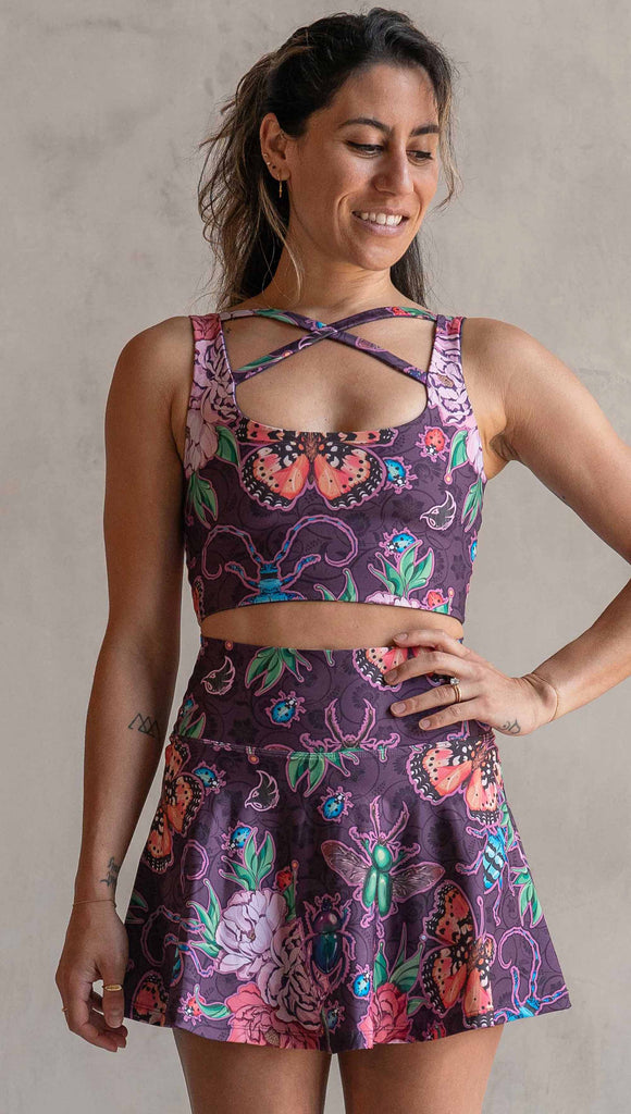Front view of model wearing WERKSHOP Enchanted Garden EnviSoft Active Skirt with hidden shorts and Pockets. The fabric is printed with original artwork by our Female Founder, Chriztina Marie. The artwork printed not the fabric features Butterflies, Beetles and Peonies over a warm fuchsia with bright bold pops of color on each beetle and Butterfly.