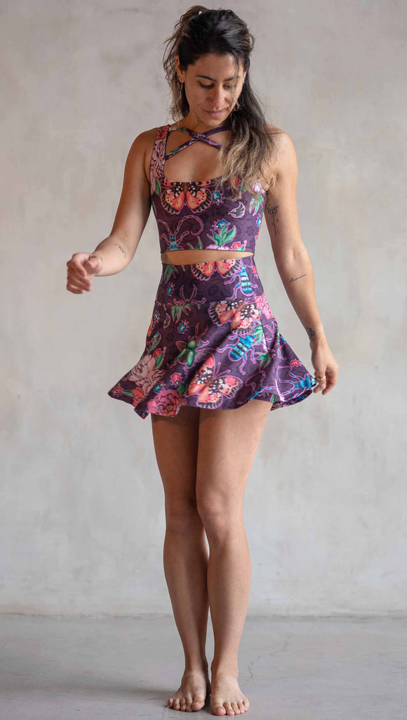 Front view of model wearing WERKSHOP Enchanted Garden EnviSoft Active Skirt with hidden shorts and Pockets. The fabric is printed with original artwork by our Female Founder, Chriztina Marie. The artwork printed not the fabric features Butterflies, Beetles and Peonies over a warm fuchsia with bright bold pops of color on each beetle and Butterfly.