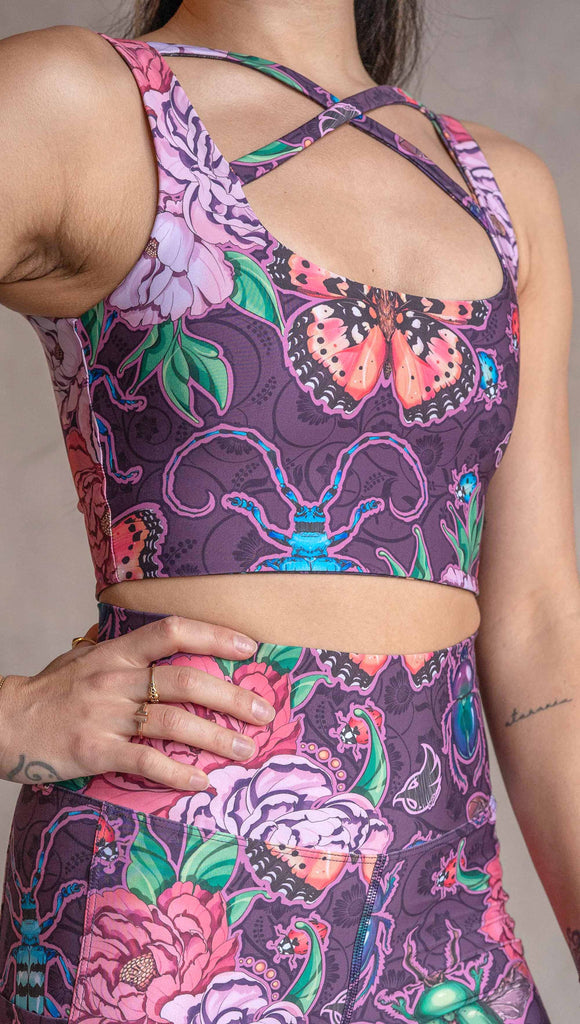 Zoomed in view of model wearing WERKSHOP Starlings and Enchanted Garden 4-Way reversible top. The fabric is printed with original artwork by Chriztina Marie. One side features European Starlings perched on a branch near a crescent moon and fireflies. The colors are warm purples with pops of pink, gold and green. The other side features Butterflies, Beetles and Peonies over a warm fuchsia with bright bold pops of color on each beetle and Butterly.