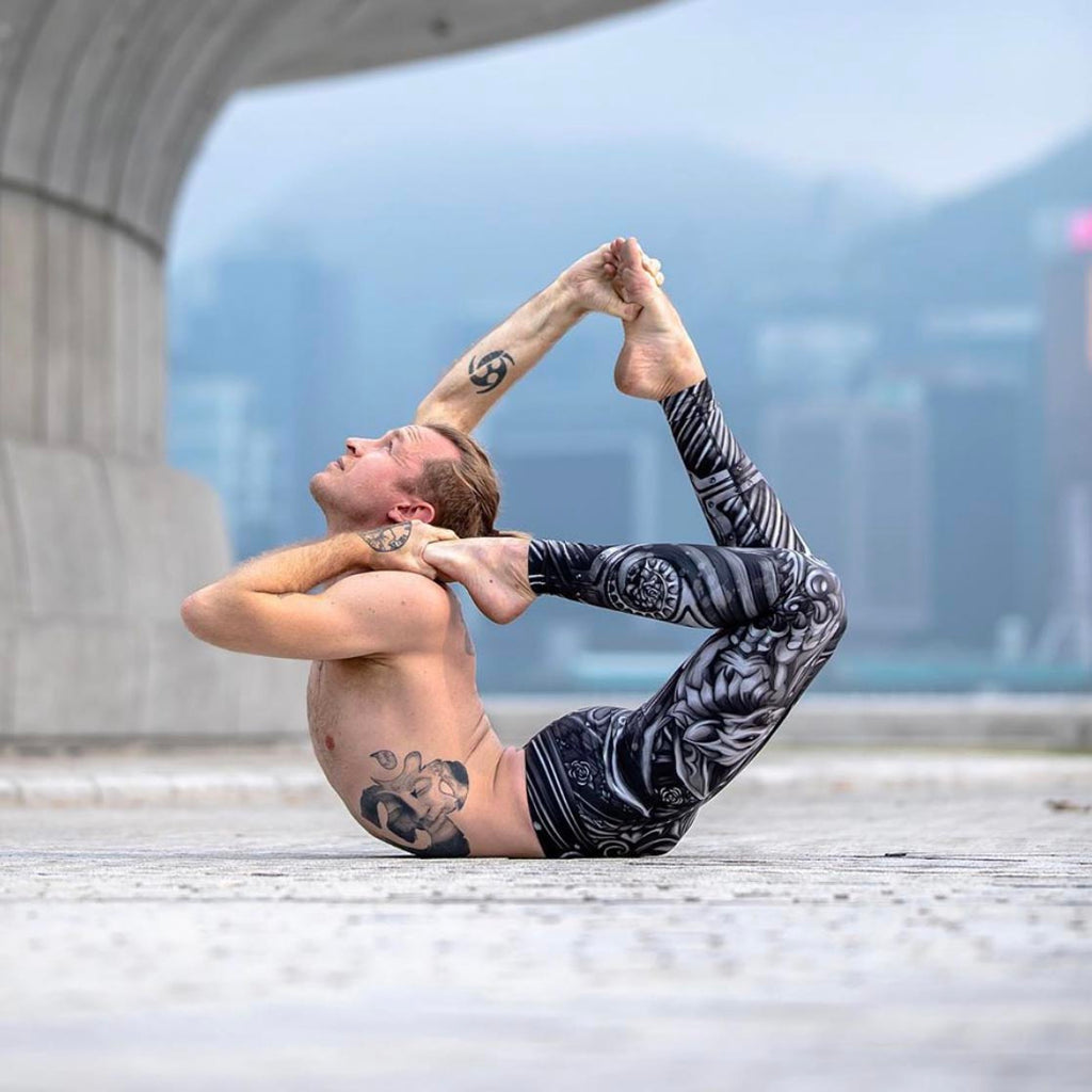 man doing upward facing bow yoga pose while wearing full length gargoyle leggings in traithlon fabric