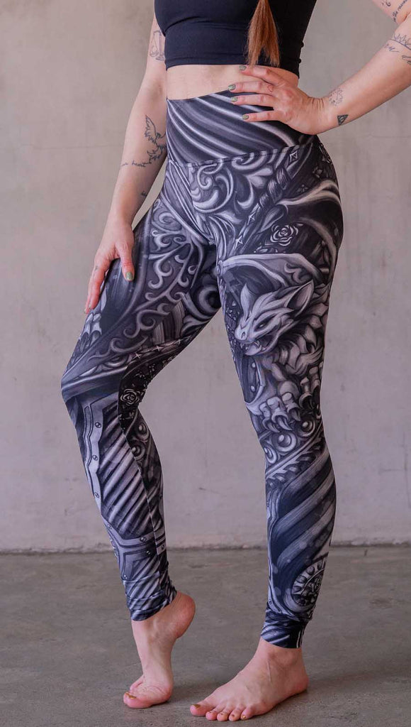 Model wearing WERKSHOP Gargoyle leggings featuring original and exclusive artwork of a black and gray gothic stone gargoyle perched on a ledge.
