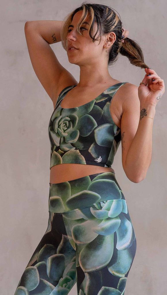 Model wearing WERKSHOP Mojave Sunset Reversible Top. One side is all green and the other side is green with bright pops of hot pink. Both sides are printed with photo-real succulents.