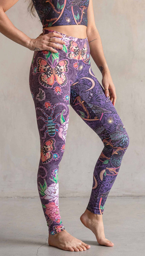 Side view of model wearing WERKSHOP Starlings and Enchanted Garden Mashup Leggings. The fabric is printed with original artwork by Chriztina Marie. Each leg features different artwork. The wearer’s left leg has European Starlings perched on a branch near a crescent moon and fireflies. The colors are warm purples with pops of pink, gold and green. The wearer’s right leg features Butterflies, Beetles and Peonies over a warm fuchsia with bright bold pops of color on each beetle and Butterly.