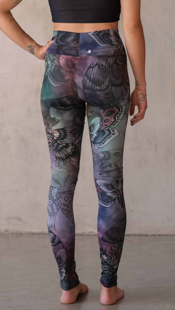 Back view of model wearing WERKSHOP Moths athlisure leggings. The artwork on the leggings is of hand drawn moths with muted pops of mauve and peach over an edgy "oil slick" inspired watercolor background.
