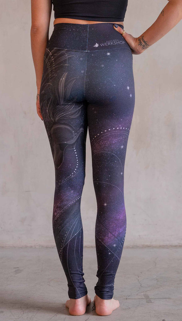 Model wearing WERKSHOP Nightmare Athleisure leggings. The artwork on the leggings features a pegasus flying through a purple galactic sky on the wearers left leg with swirls and a full moon just below the left knee.