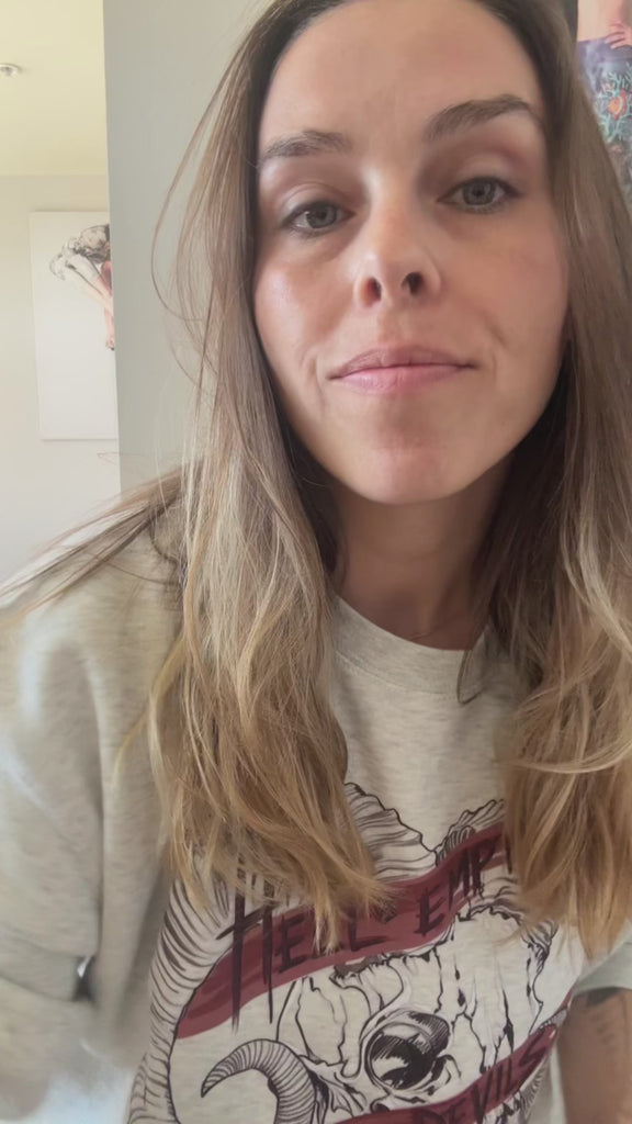 Video showing a girl wearing a oatmeal color unisex pullover. Featuring a gothic skull and the quote, "Hell is Empty and the Devils Are All Here" from the Temptest by William Shakespeare