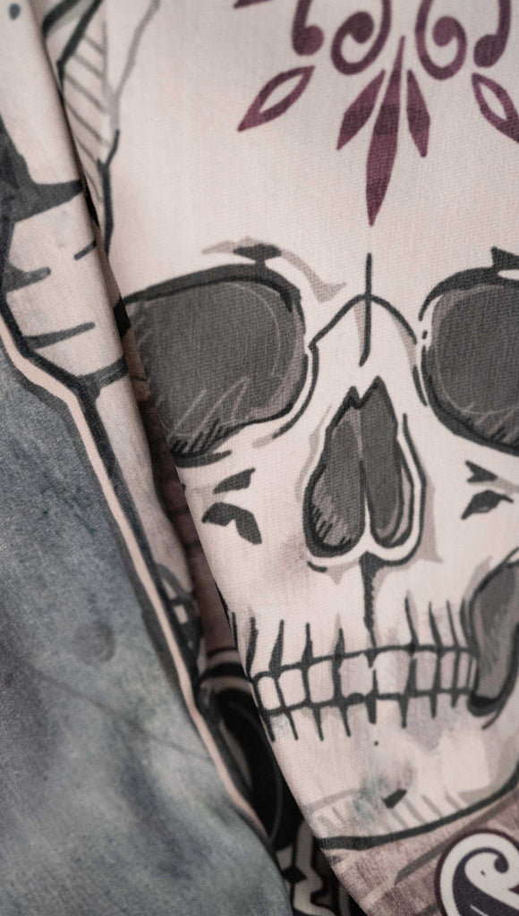 Zoomed in image of chenille WERKSHOP Tapestry with original bookish artwork. There is a tombstone with the phrase, "Read in Peace" and "Famous last words: just one more chapter" .. The bottom of the tombstone has an open book with roses framing the base.