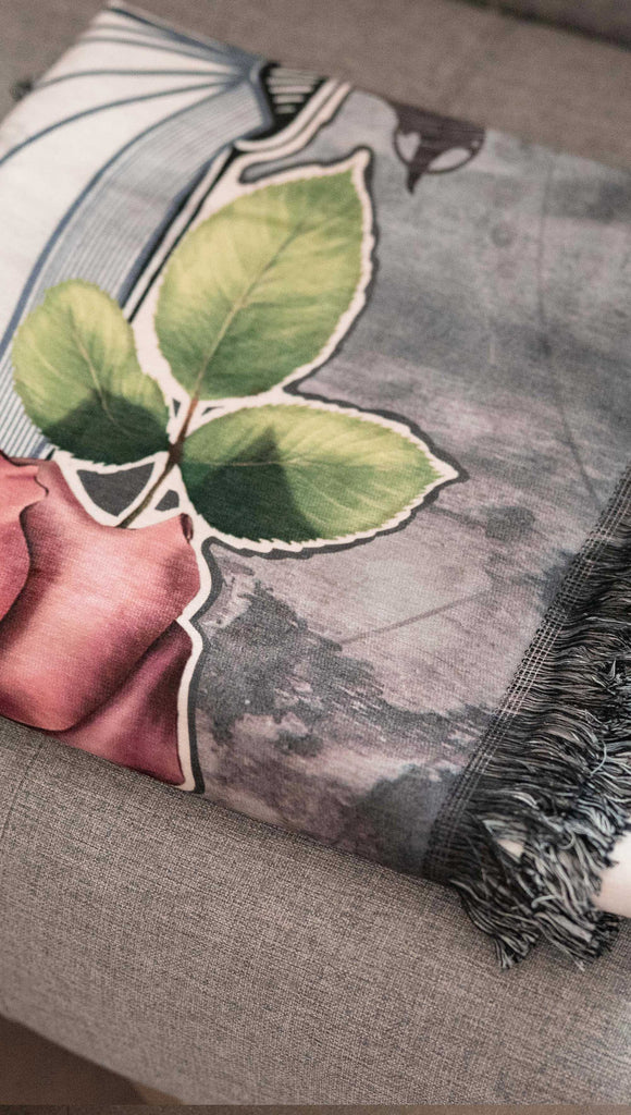 Chenille WERKSHOP Tapestry with original bookish artwork. There is a tombstone with the phrase, "Read in Peace" and "Famous last words: just one more chapter" .. The bottom of the tombstone has an open book with roses framing the base. (folded on a couch)