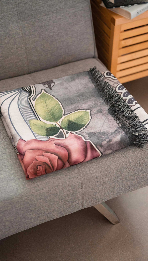 Decorative blanket with a rose design on a gray sofa.
