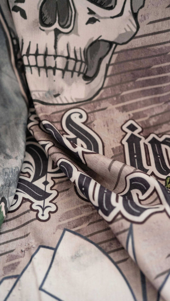 Zoomed in image of chenille WERKSHOP Tapestry with original bookish artwork. There is a tombstone with the phrase, "Read in Peace" and "Famous last words: just one more chapter" .. The bottom of the tombstone has an open book with roses framing the base.