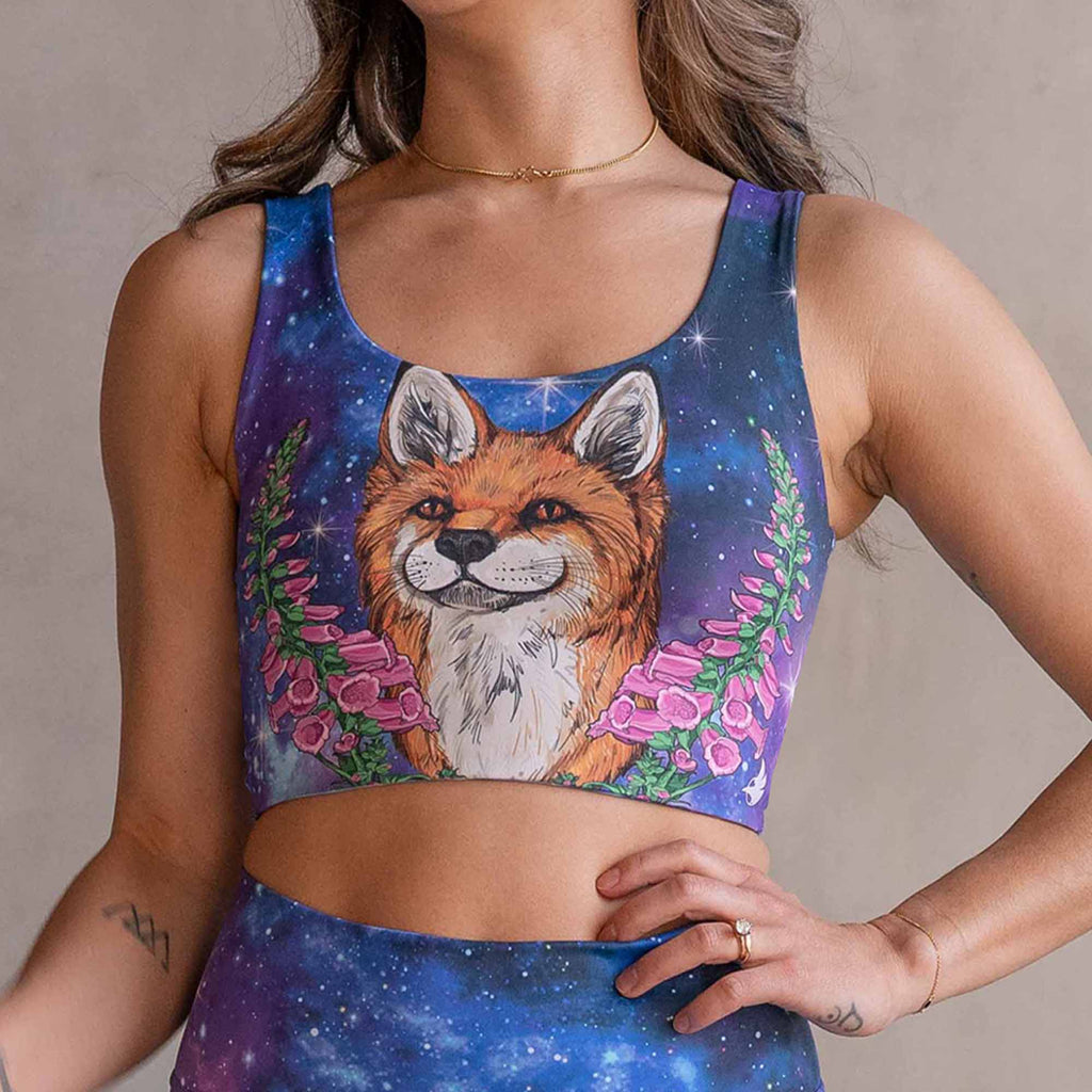 Girl wearing WERKSHOP X Save A Fox reversible top. The top features original artwork of a coy red fox surrounded by foxgloves over a galactic sky background. 