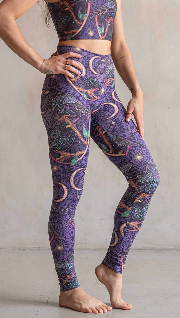 Side view of model wearing WERKSHOP Starlings Athleisure Leggings. The fabric is printed with original artwork by our Female Founder, Chriztina Marie. Featuring European Starlings perched on a branch near a crescent moon and fireflies. The colors are warm purples with pops of pink, gold and green.