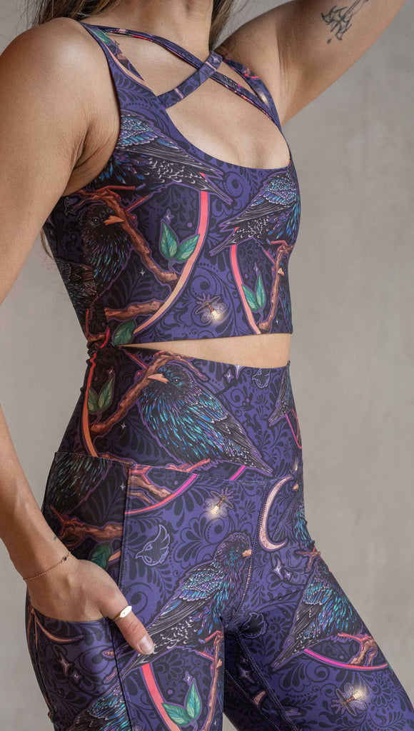 Zoomed in view of model wearing WERKSHOP Starlings EnviSoft leggings with pockets. The fabric is printed with original artwork by our Female Founder, Chriztina Marie. Featuring European Starlings perched on a branch near a crescent moon and fireflies. The colors are warm purples with pops of pink, gold and green.