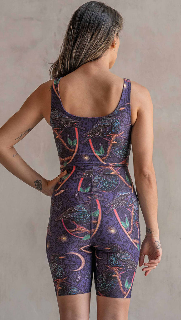 Back view of model wearing WERKSHOP Starlings and Enchanted Garden 4-Way reversible top. The fabric is printed with original artwork by Chriztina Marie. One side features European Starlings perched on a branch near a crescent moon and fireflies. The colors are warm purples with pops of pink, gold and green. The other side features Butterflies, Beetles and Peonies over a warm fuchsia with bright bold pops of color on each beetle and Butterly.