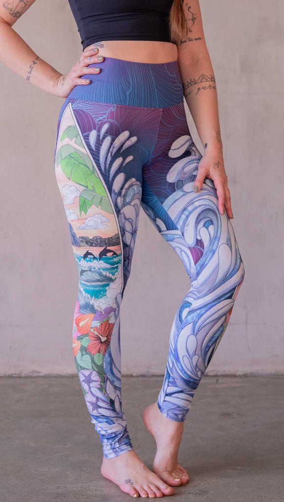 Model wearing WERKSHOP Surfboard leggings featuring Model wearing WERKSHOP Onyx leggings featuring original and exclusive polygon artwork that has a dark gray and black at the waistband to light gray ombre fade below the knee. The design is asymmetrical with the WERKSHOP eagle logo is on the wearers left hip. 