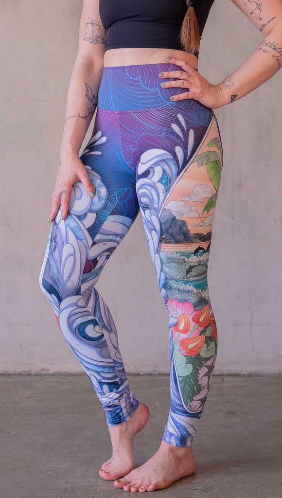 Model wearing WERKSHOP Surfboard leggings featuring Model wearing WERKSHOP Onyx leggings featuring original and exclusive polygon artwork that has a dark gray and black at the waistband to light gray ombre fade below the knee. The design is asymmetrical with the WERKSHOP eagle logo is on the wearers left hip. 