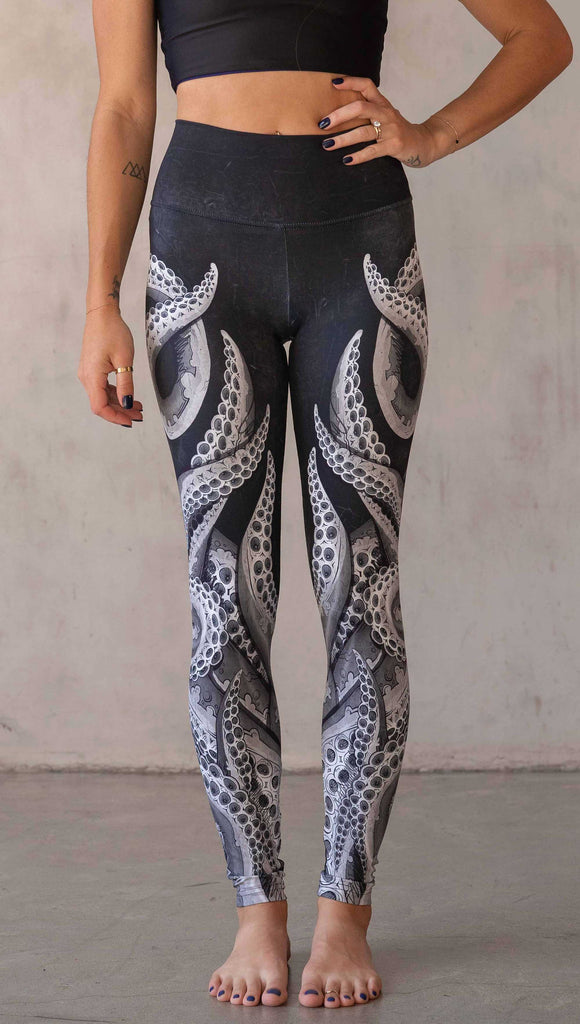 Front view of model wearing WERKSHOP Tentacles Athleisure Leggings. The artwork on the leggings features hand drawn tentacles wrapping up and around each leg in colors of black and white with distressed texture.