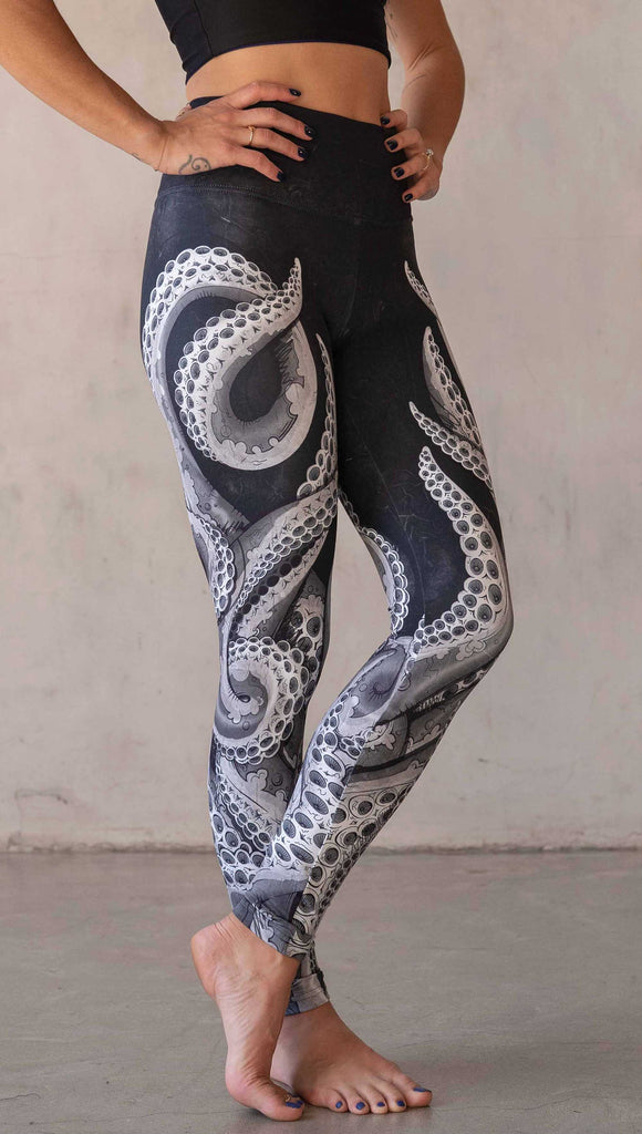 Model wearing WERKSHOP Tentacles Athleisure Leggings. The artwork on the leggings features hand drawn tentacles wrapping up and around each leg in colors of black and white with distressed texture.
