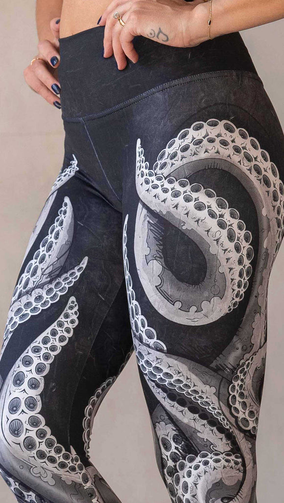 Zoomed in view of model wearing WERKSHOP Tentacles Athleisure Leggings. The artwork on the leggings features hand drawn tentacles wrapping up and around each leg in colors of black and white with distressed texture.